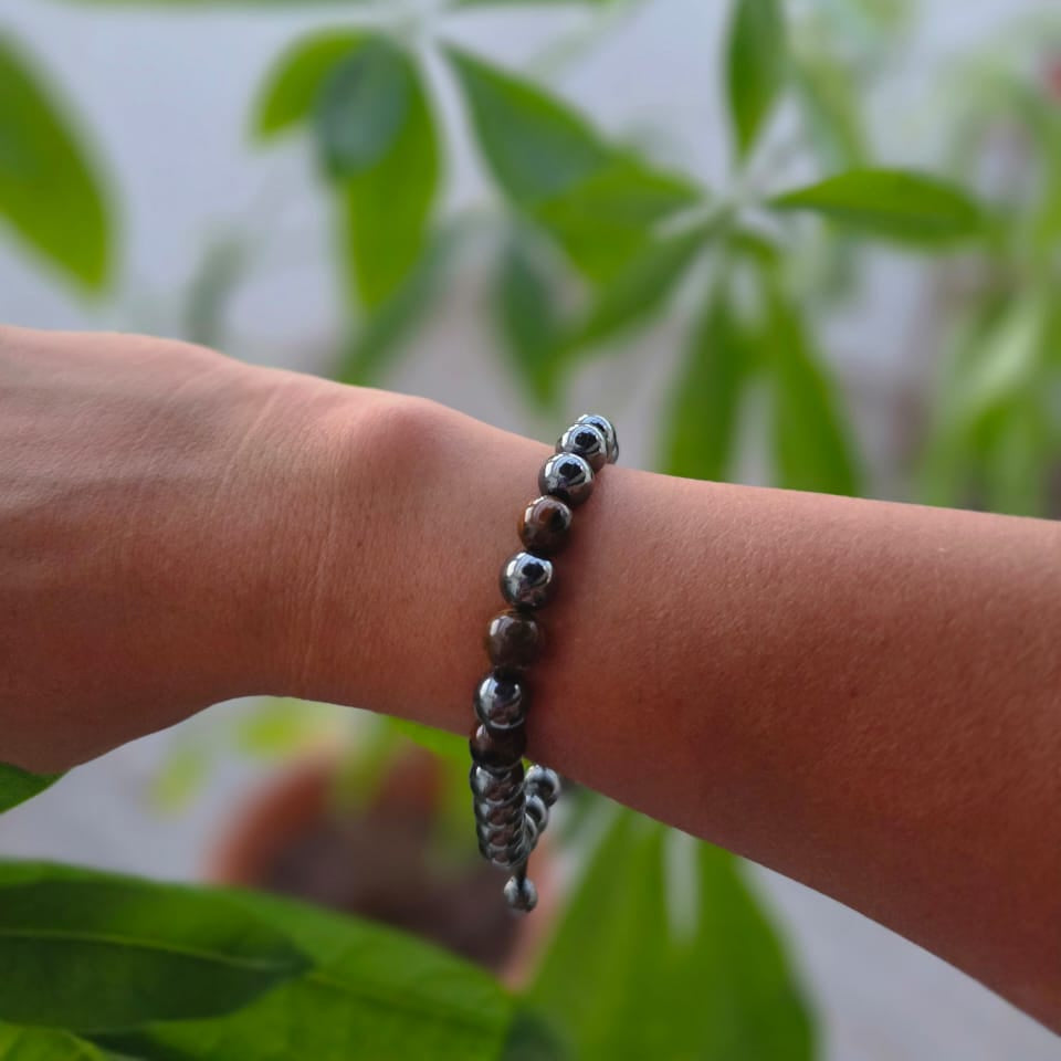 Pulsera de hematita natural de 8 mm llevada en la muñeca, con piedras en tonos gris metálico, diseño elegante y minimalista para uso diario