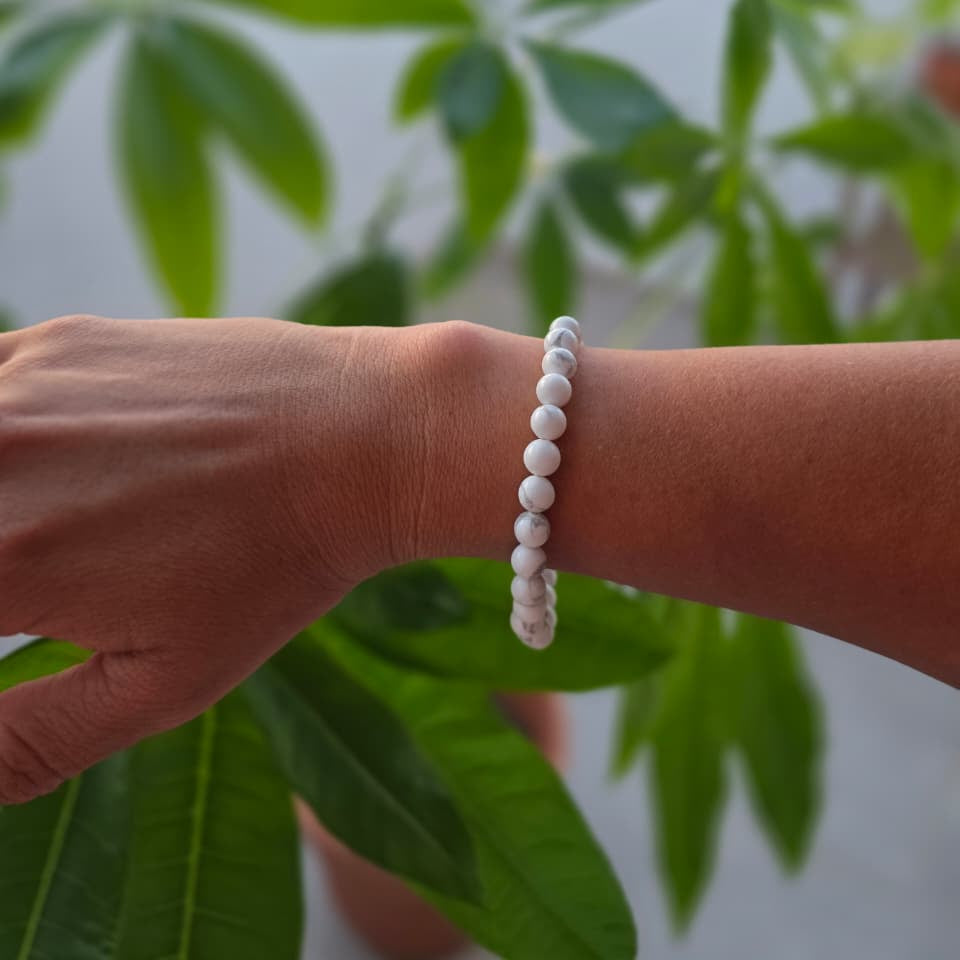 Pulsera de howlita natural de 6 mm llevada en la muñeca, con piedras blancas y vetas grises, diseño elegante y minimalista