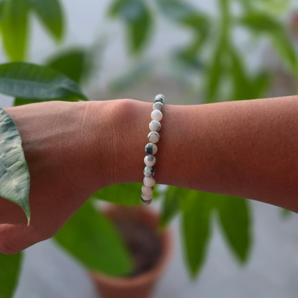 Pulsera de ágata árbol natural de 6 mm llevada en la muñeca, con piedras en tonos blancos, grises y marrones, patrones naturales y diseño elegante