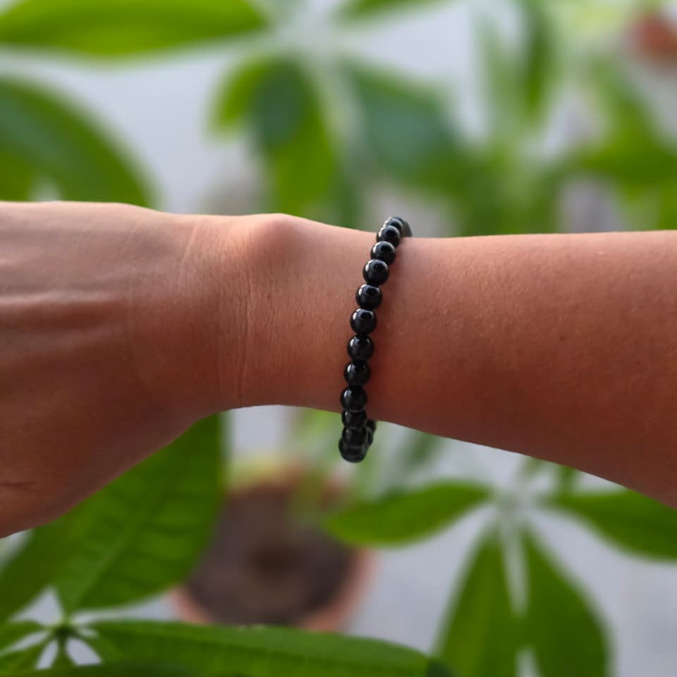 Pulsera de ónix natural de 6 mm llevada en la muñeca, con piedras negras de acabado elegante, diseño minimalista y atemporal